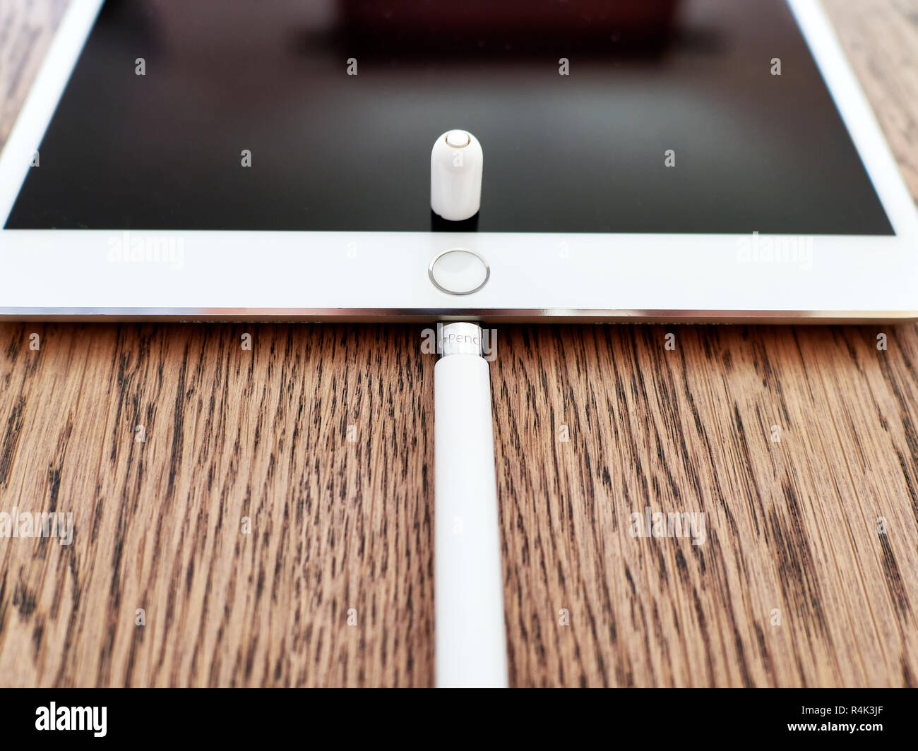 Matita di Apple e il suo cappuccio su un iPad di colore bianco su una superficie in legno Foto Stock