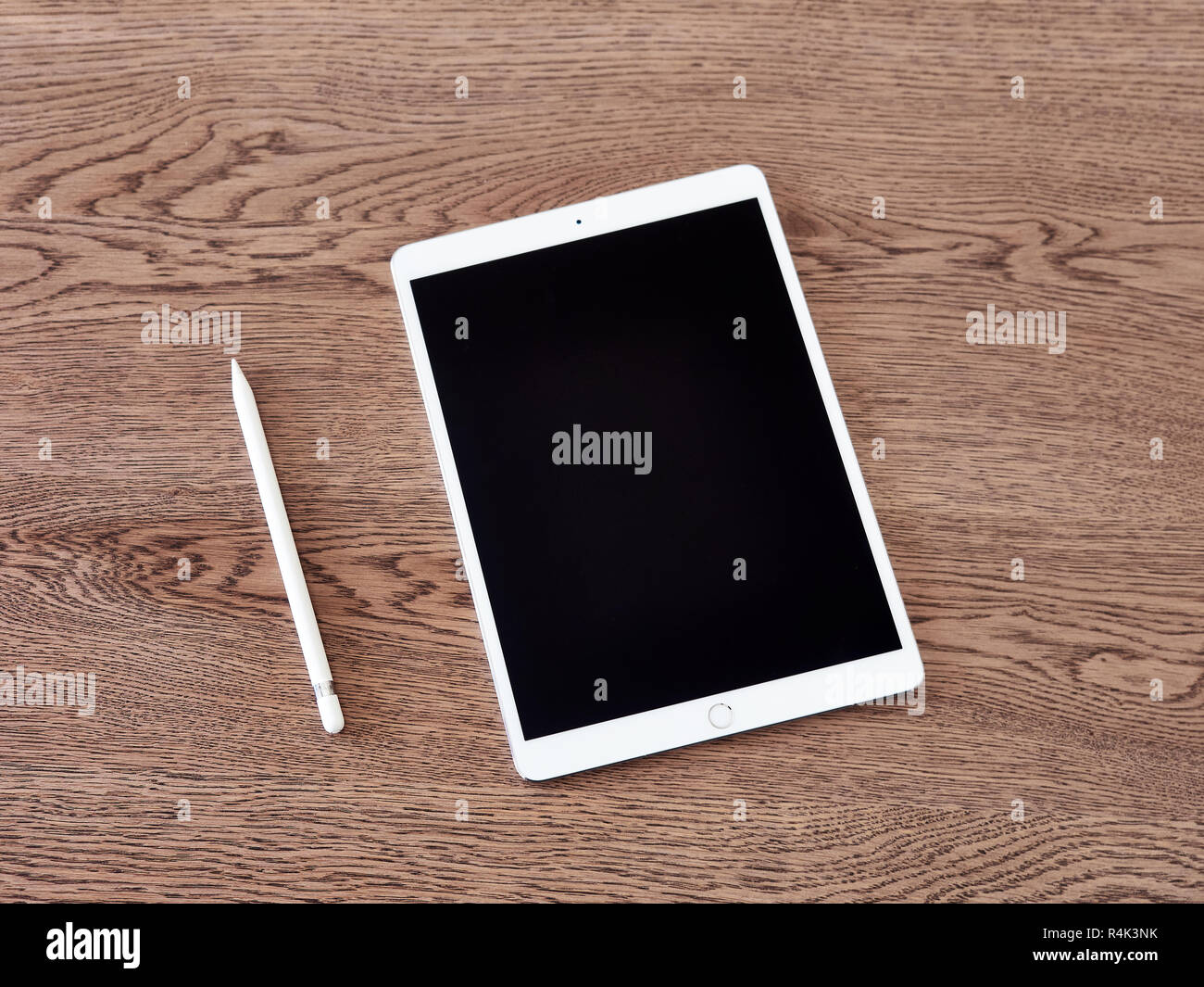 Matita di Apple e il suo cappuccio su un iPad di colore bianco su una superficie in legno Foto Stock