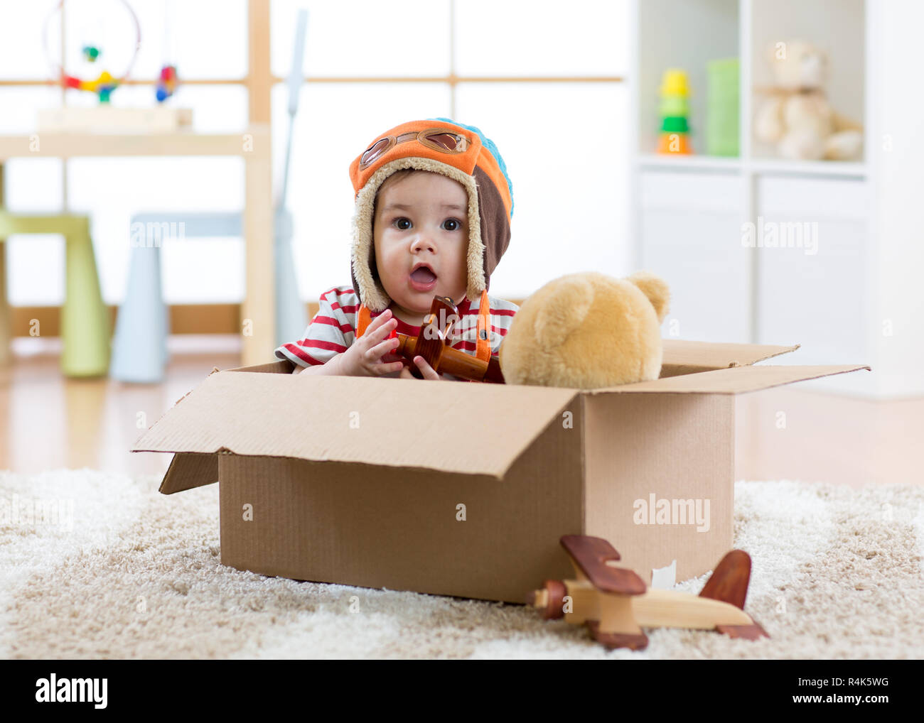 Aviatore pilota baby boy con Teddy bear toy e piani svolge in scatola di cartone Foto Stock