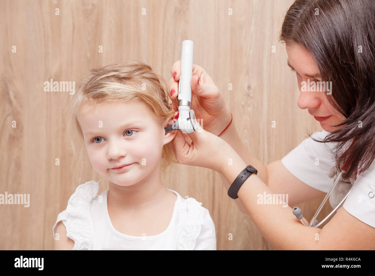 Femmina esamina pediatra bambina l orecchio. Medico utilizzando un otoscopio o auriscope per controllare il canale uditivo e la membrana del timpano. Bambino ENT concetto di controllo Foto Stock