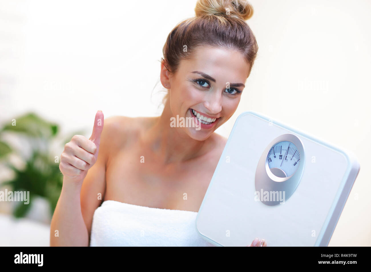 Donna felice azienda bilancia da bagno in stanza da bagno Foto Stock