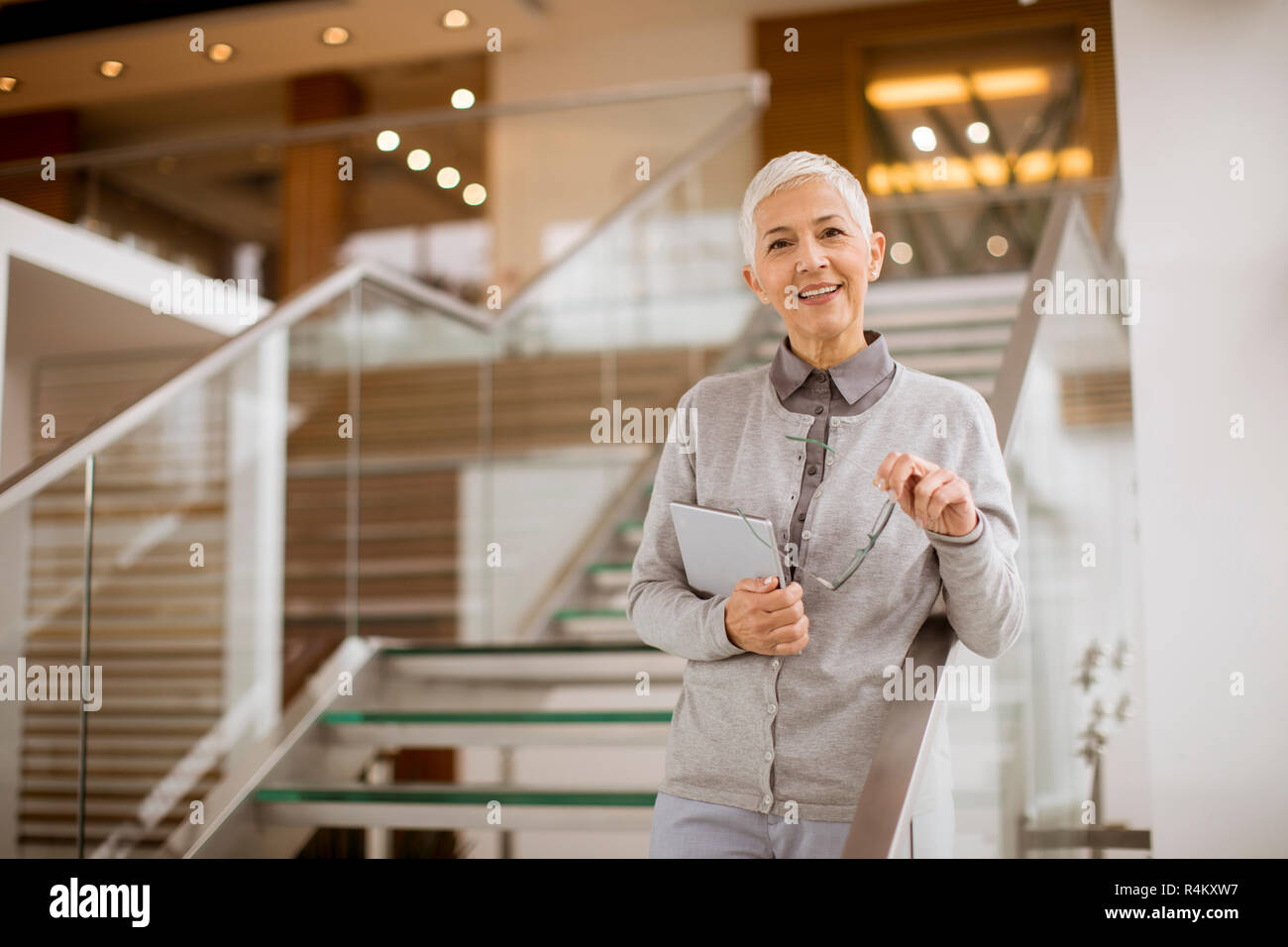 Ritratto di senior imprenditrice in piedi in un ufficio moderno e azienda tavoletta digitale Foto Stock