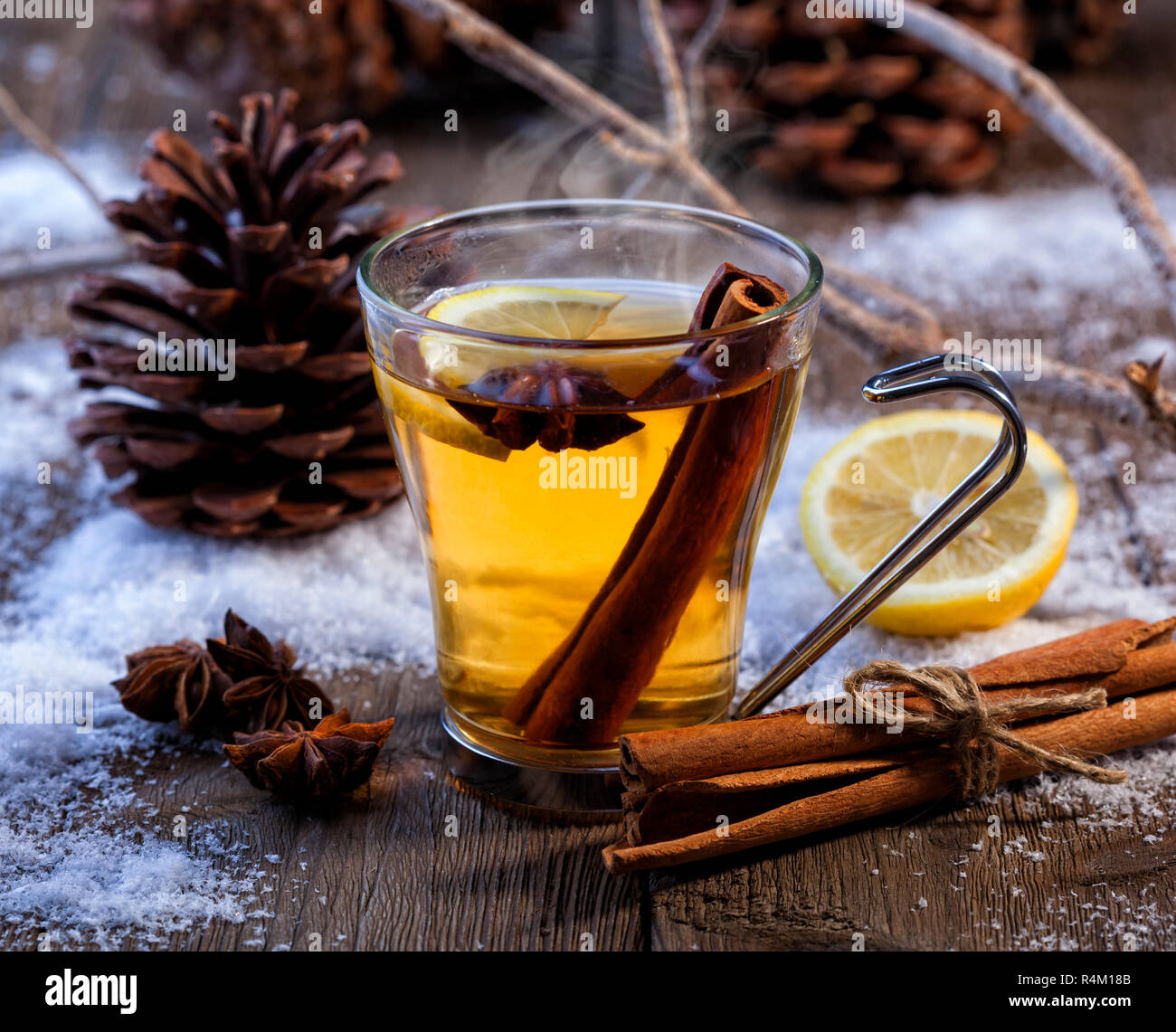 Inverno caldo bevanda con cannella, anice e limone. Scena invernale con pigne e neve. Foto Stock