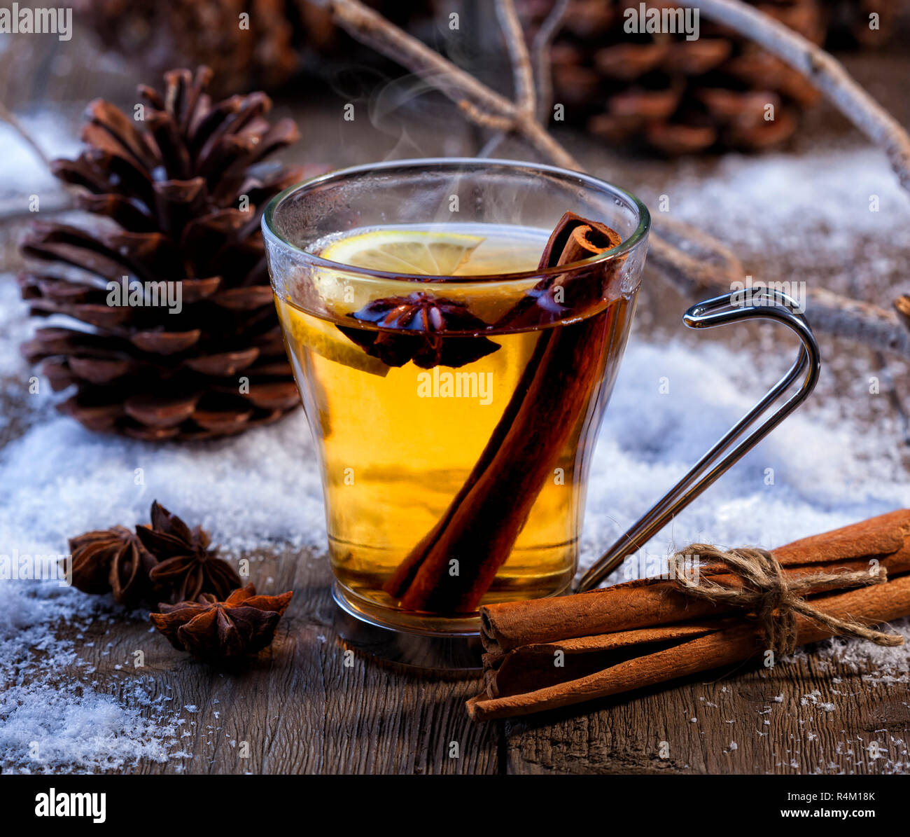 Inverno caldo bevanda con cannella, anice e limone. Scena invernale con pigne e neve. Foto Stock