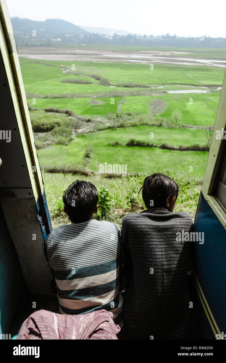 27 febbraio 2018 Amritsar, India. due ragazzi indiani in treno e porte ant lookint bel paesaggio verde. Foto Stock