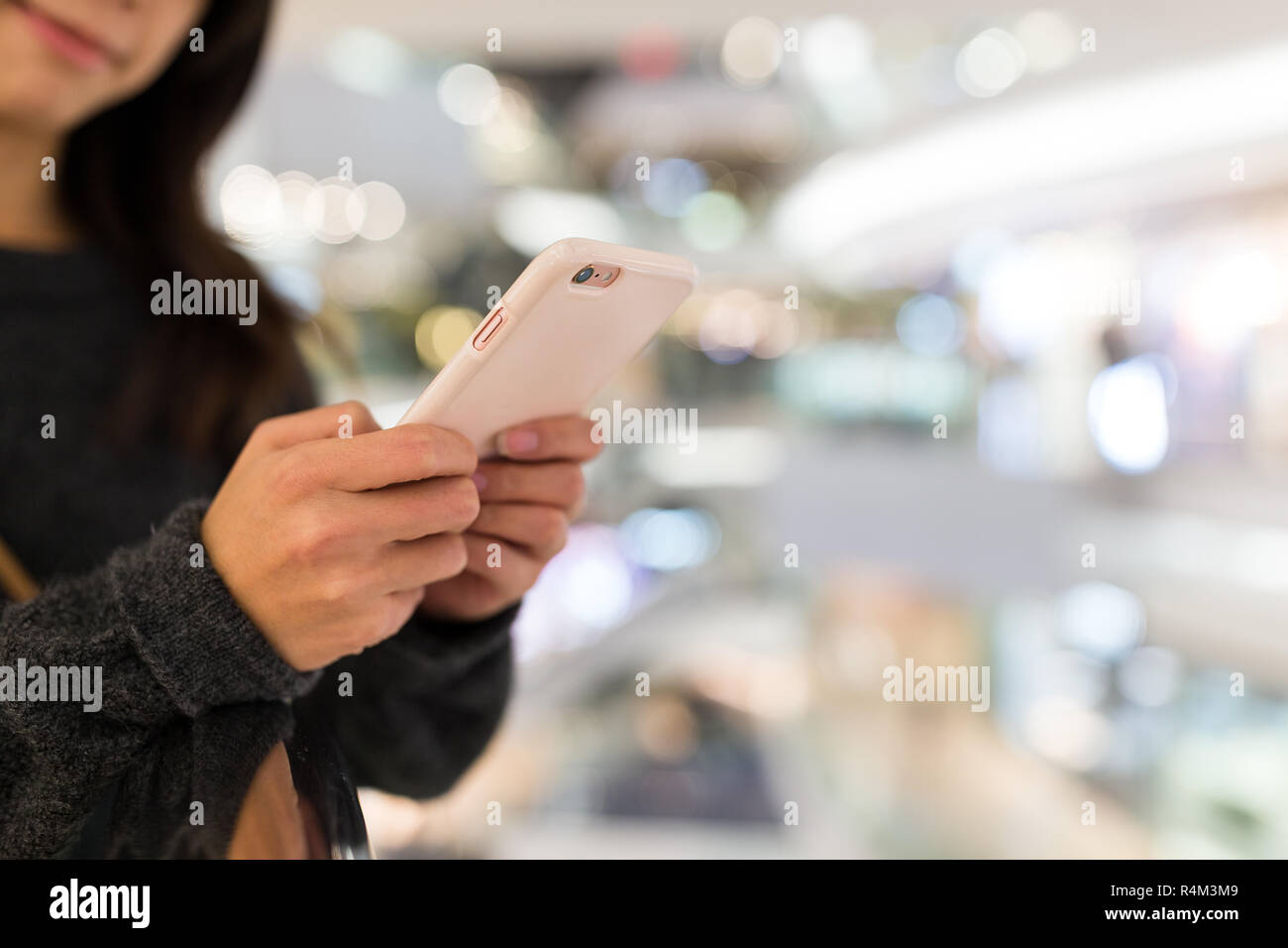 Donna uso del telefono cellulare nel centro commerciale per lo shopping Foto Stock