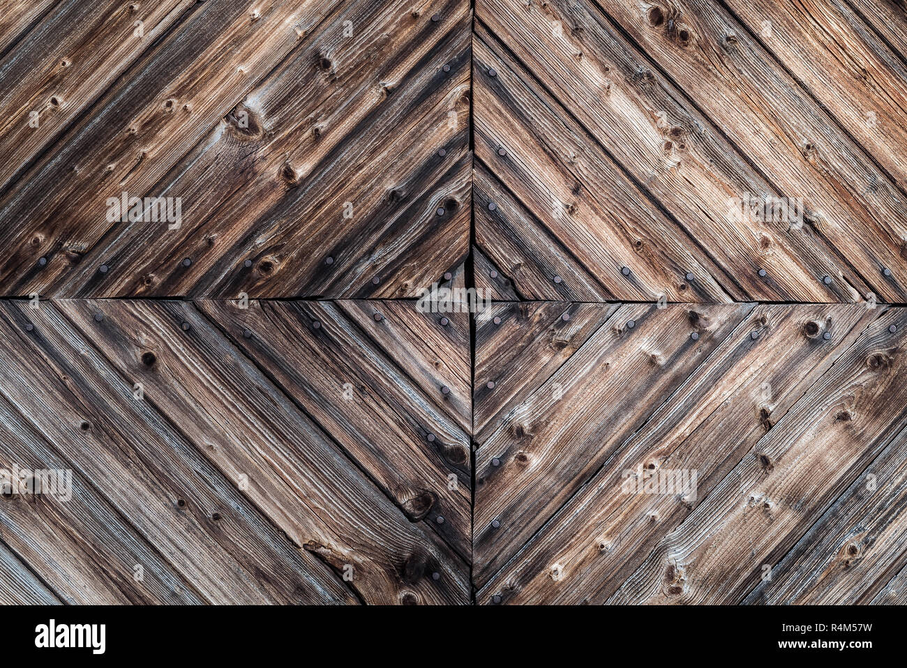 Primo piano di un rustico di età compresa tra la parete di legno con uno sfondo con rivestimenti di legno decorativo i dettagli del progetto e chiodi arrugginiti con antichi, vernice scura Foto Stock