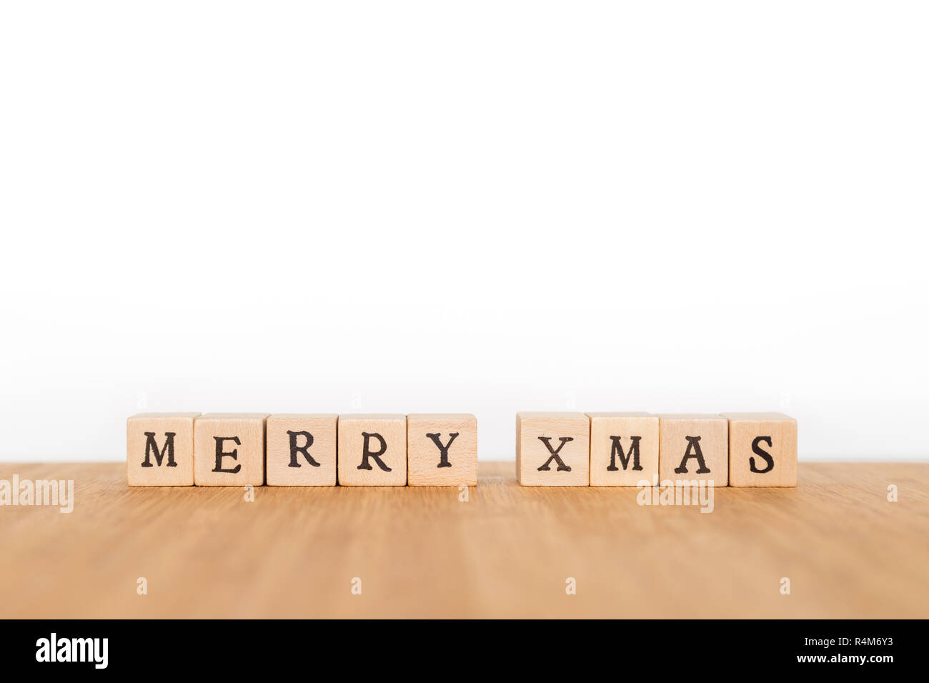 Focus sulla frase 'Buon Natale' fatta di blocco di legno dice con lettere su una tavola di legno. Profondità di campo. Copia dello spazio. Foto Stock