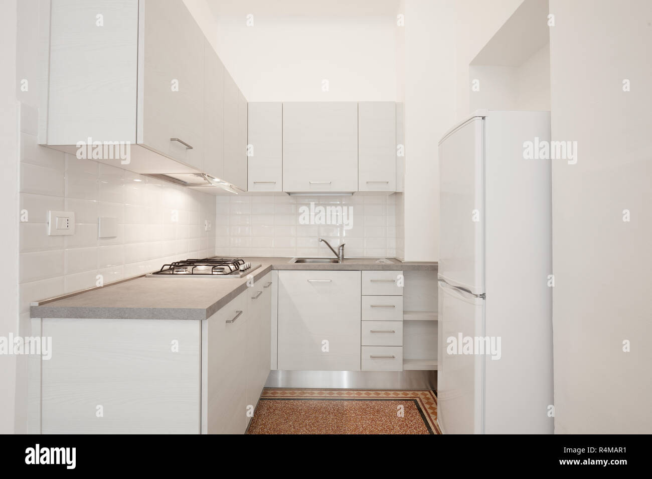 Bianco da cucina in legno con la pietra grigia top in appartamento ristrutturato interno Foto Stock