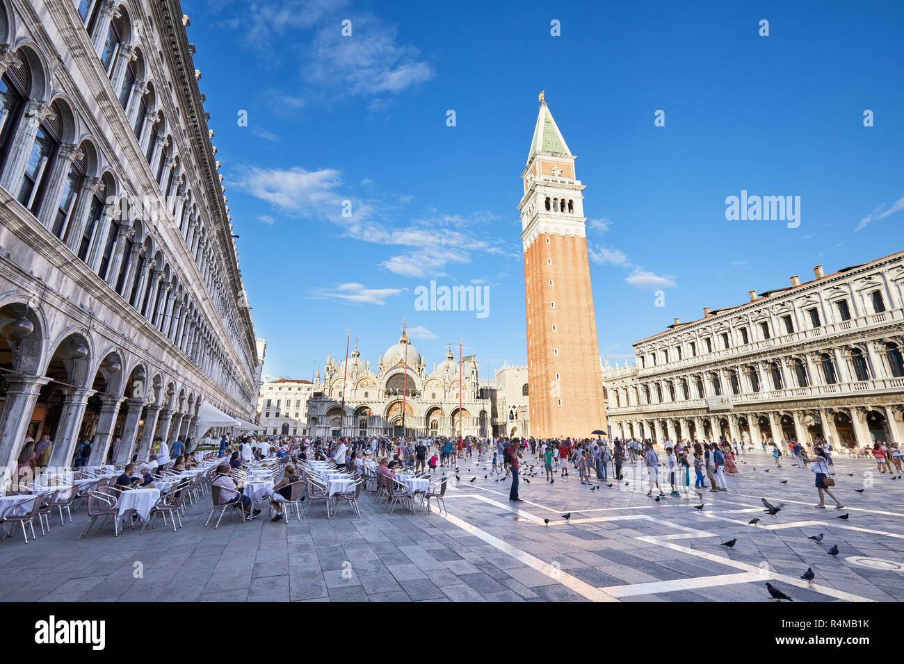 Venezia, Italia - 12 agosto 2017: Piazza San Marco con la tabella sul marciapiede e gente che cammina, cielo blu in una soleggiata giornata estiva in Italia Foto Stock