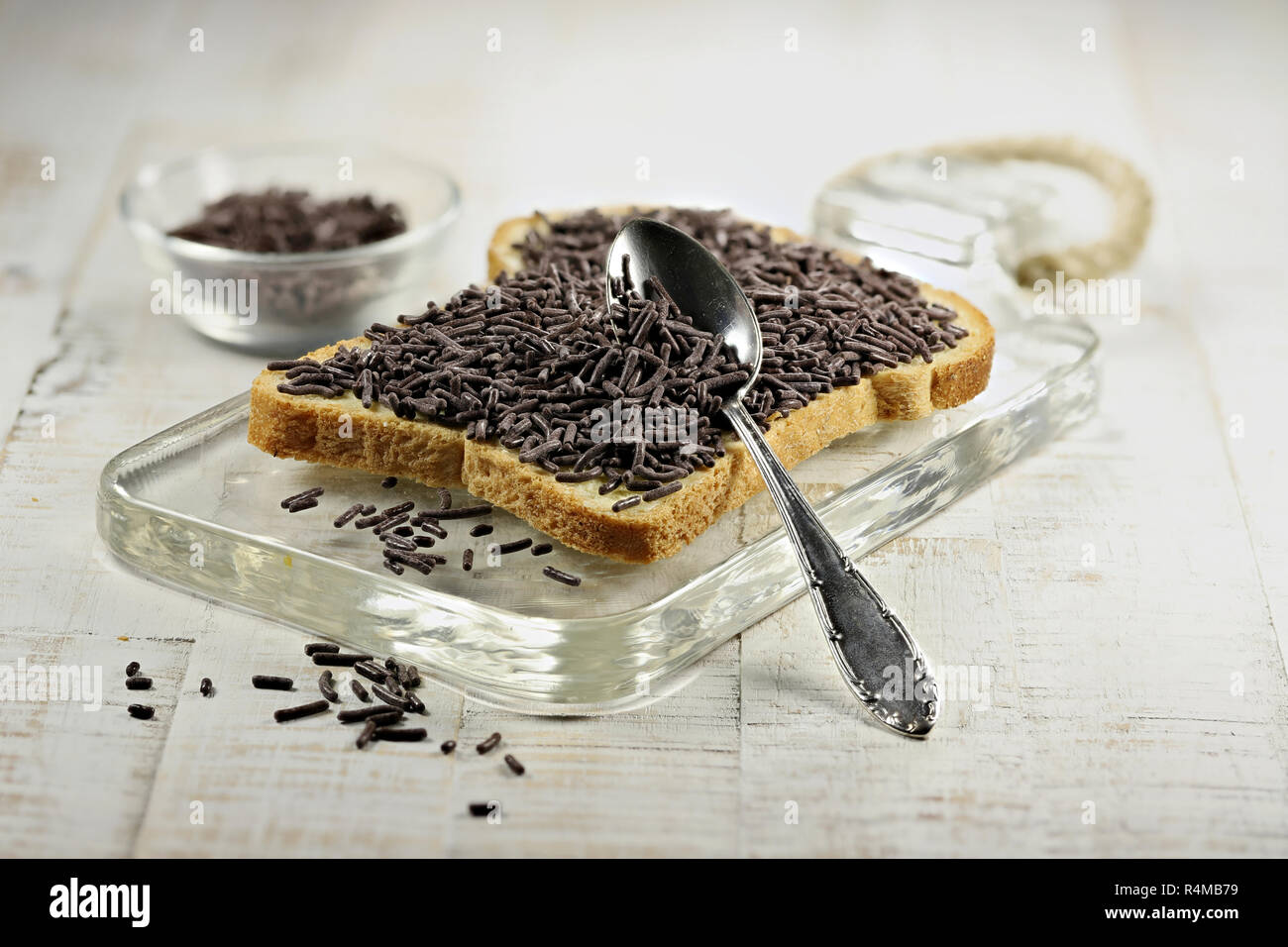 Olandese pane bianco con hagelslag (cioccolato spruzza) topping sul bordo del vetro Foto Stock