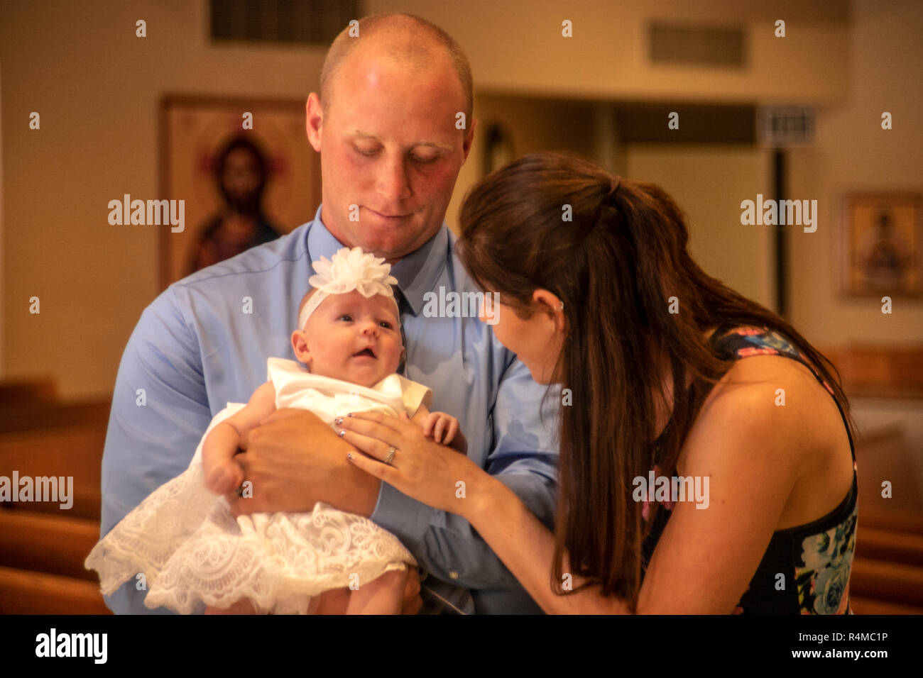 Una coppia con un figlio neonato attendere di partecipare al loro bambino il battesimo ad una Laguna Niguel, CA, chiesa cattolica. Foto Stock
