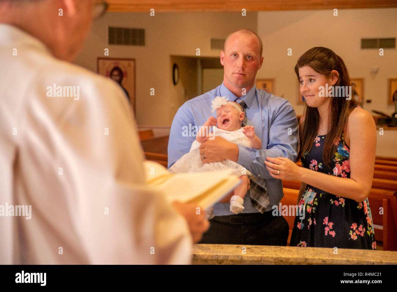 Una coppia con un figlio neonato partecipare al loro bambino il battesimo prima di un diacono derubato in una Laguna Niguel, CA, chiesa cattolica. Foto Stock