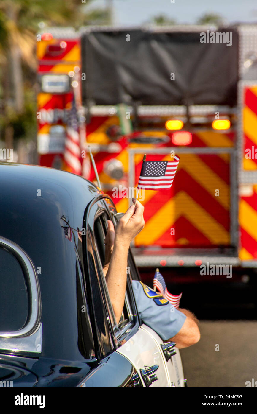 Una bandiera americana sventola dalla finestra di un antico 1951 auto della polizia in quanto segue un incendio del motore in un quarto di luglio sfilata in Newport Beach, CA. Foto Stock