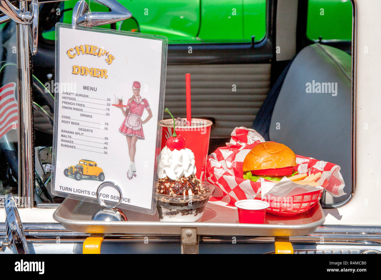 1950 prezzi per le repliche in plastica di auto-hop cibo su un conducente porta-vassoio decorare un vassoio di vetro su un 1954 Chevrolet, evocando un'era da tempo passato a un classico auto show di Huntington Beach, CA. Foto Stock