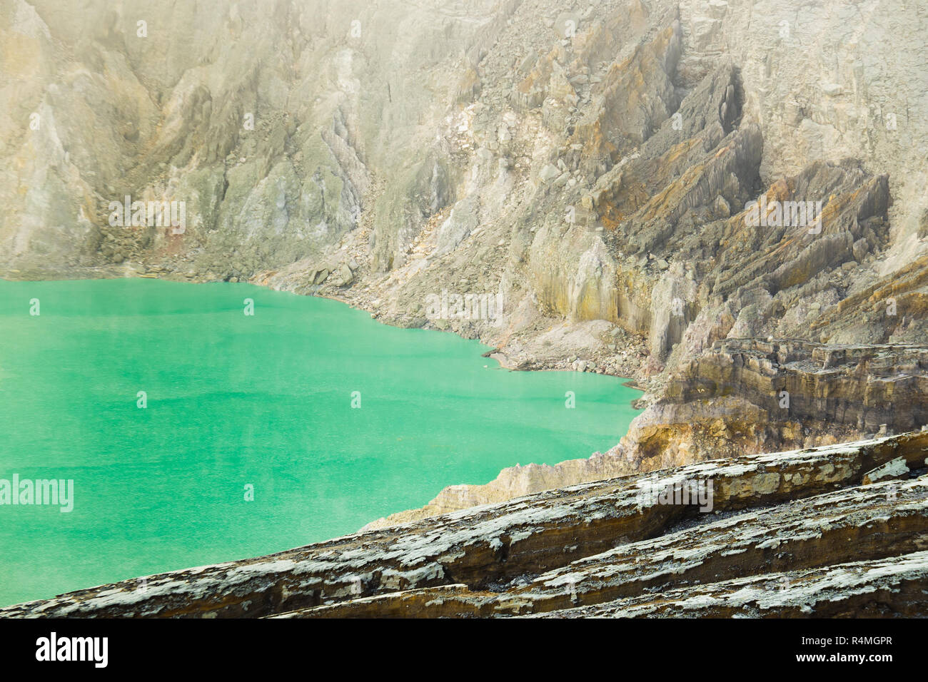 Acido solforico verde lago circondato da texture dettagliate di montagna Ijen il cratere, Banyuwangi, Indonesia Foto Stock