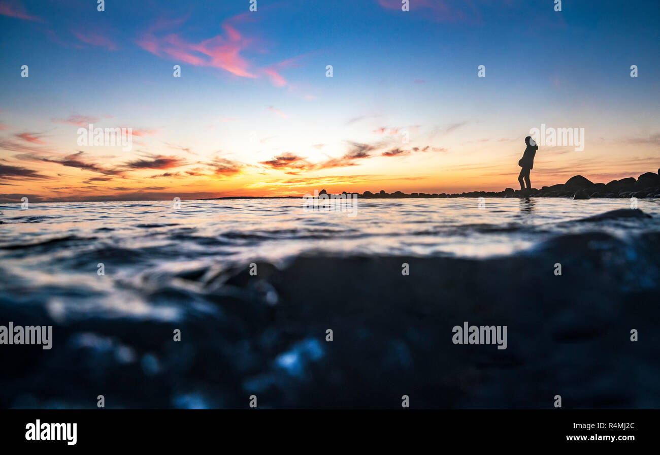 Donna in piedi lungo la costa dell'Oceano Pacifico, fotografati da metà sott'acqua. Foto Stock