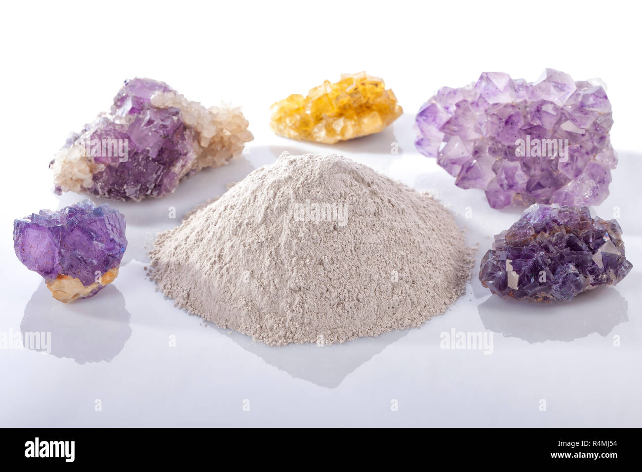 Una pila di prodotti trasformati a base di polvere di fluoro spar circondato da minerali pietre di fluorite isolato su bianco. Foto Stock