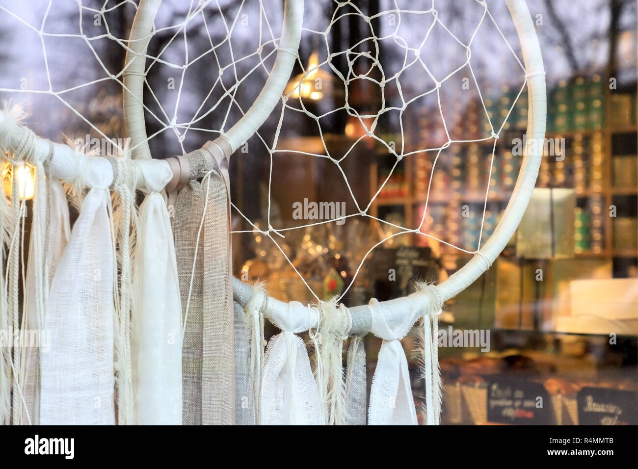 Due sogno tessuto catturatori appeso dietro un negozio di vetro anteriore dove possiamo vedere il negozio di interni in un flou sfondo. Foto Stock