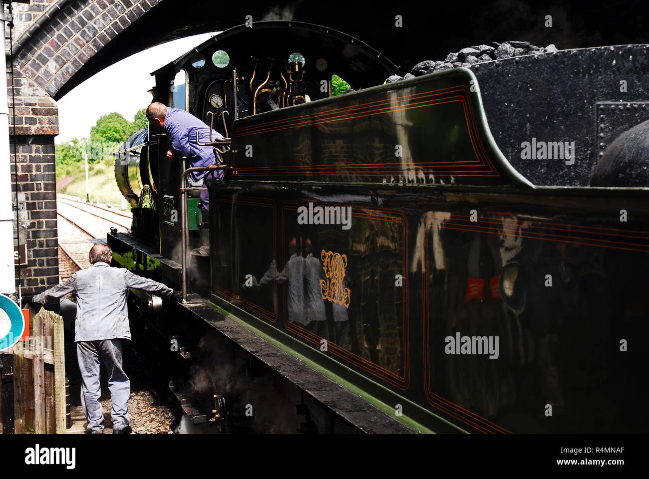 Il driver del motore e vigile del fuoco preparare la città di Truro locomotiva a vapore per il suo prossimo viaggio in Gloucestershire e Warwickshire Steam Railway, REGNO UNITO Foto Stock