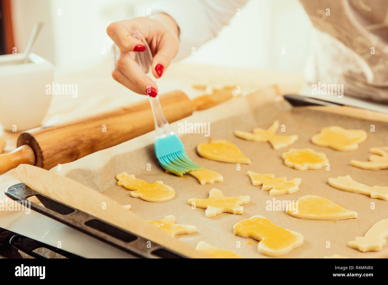 Donna di strisci mano uovo sbattuto su biscotti fatti in casa Foto Stock