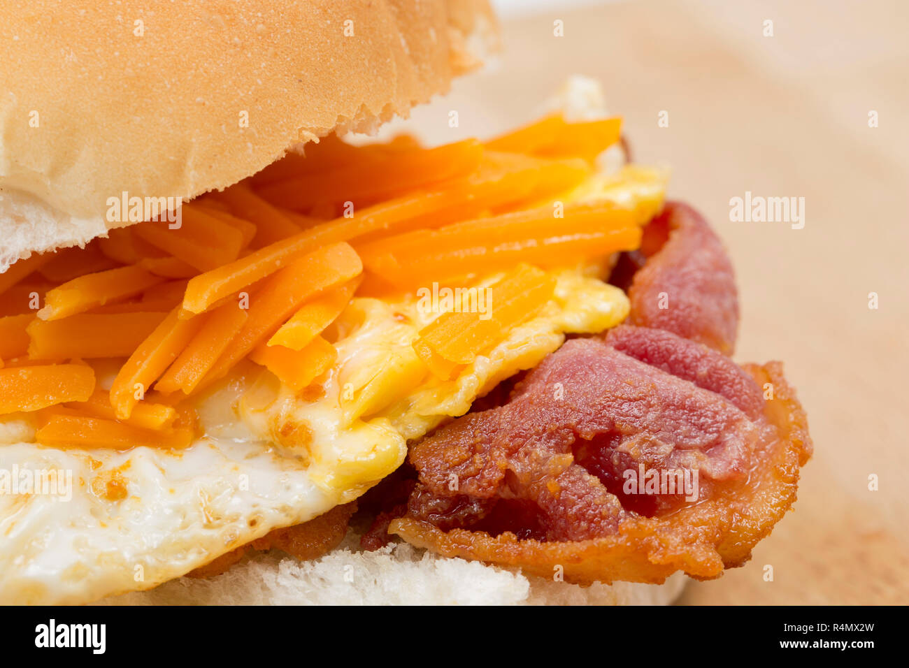 Fumato back bacon prodotte nella UE e acquistato da un supermercato del Regno Unito che è stato fritto e collocato su un rotolo di pane con un uovo fritto e una spolverata Foto Stock