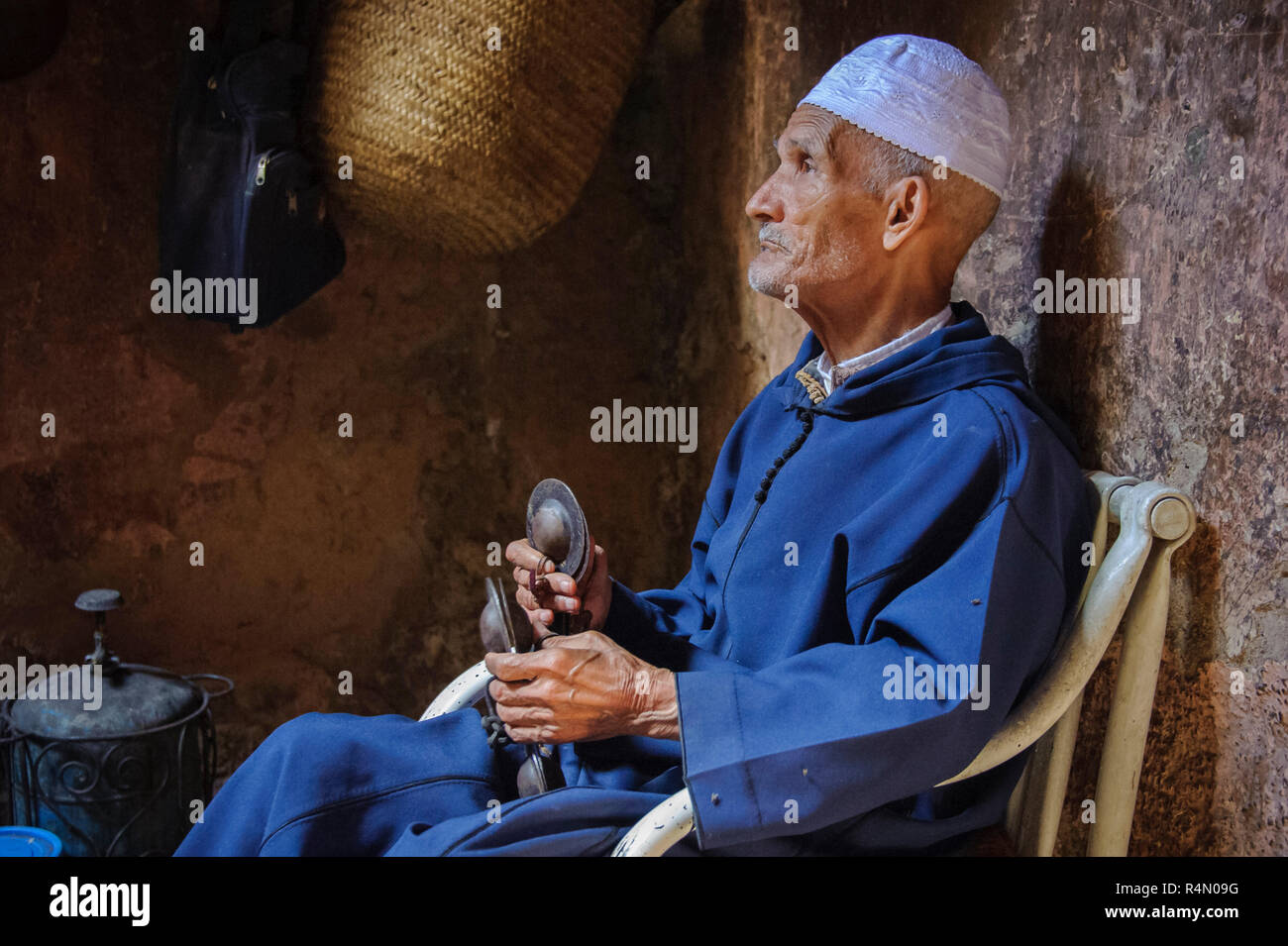 18-04-11. Marrakech, Marocco. Un uomo anziano vestito in abiti tradizionali e una calotta, riproduce krakebs, grandi castanet ferro-come musicale instrum Foto Stock