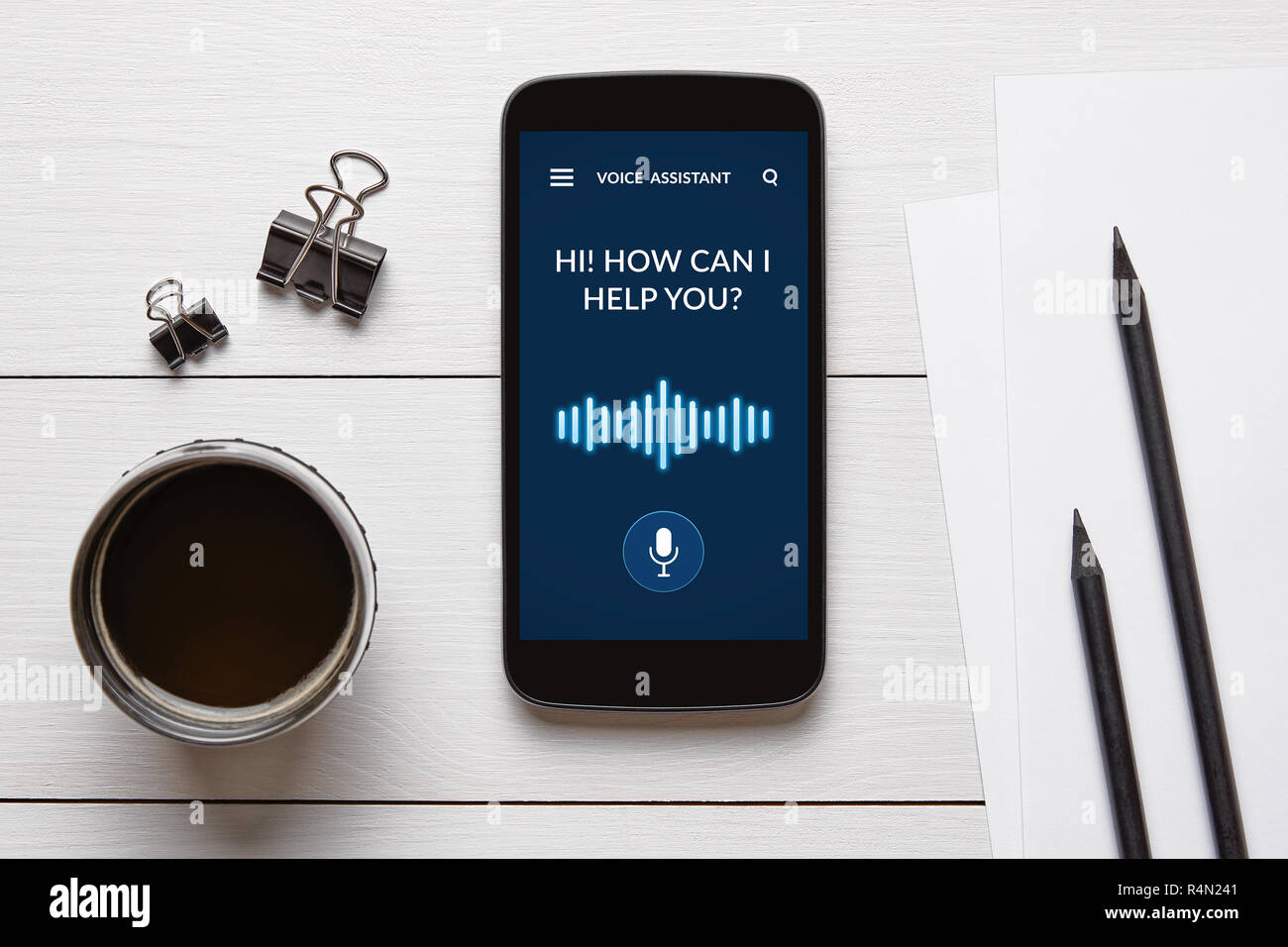 Assistente vocale concetto su smart phone schermo con oggetti di Office su bianco tavolo in legno. Tutti i contenuti della schermata è progettato da me. Lay piatto Foto Stock