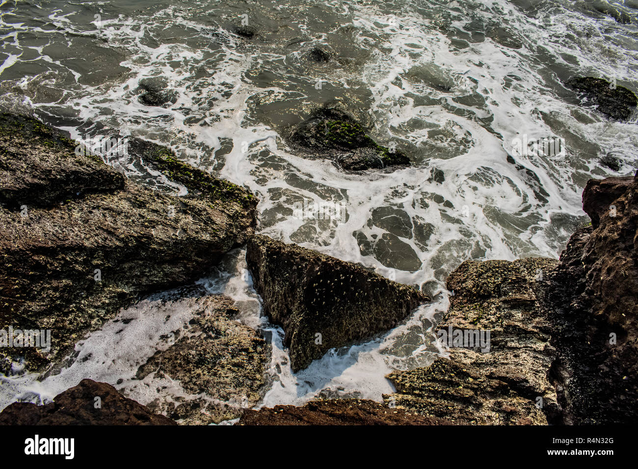 Yarada spiaggia con le onde dell'oceano indiano che si infrangono sulle rocce e le pietre della riva. Foto a lunga esposizione con acqua liscia e setosa e roccia sullo sfondo. Foto Stock