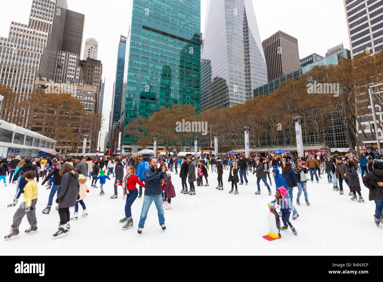 Famiglie, persone amici pattinaggio su ghiaccio in inverno villaggio al Bryant Park, Manhattan, New York City. Foto Stock