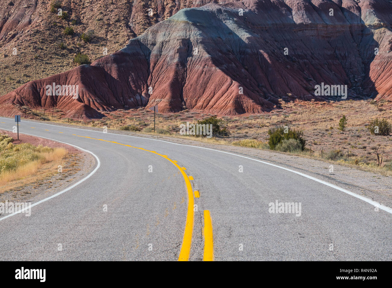 La curvatura strada che conduce in un variopinto paesaggio del deserto vicino Abiquiu, Nuovo Messico del sud-ovest americano Foto Stock