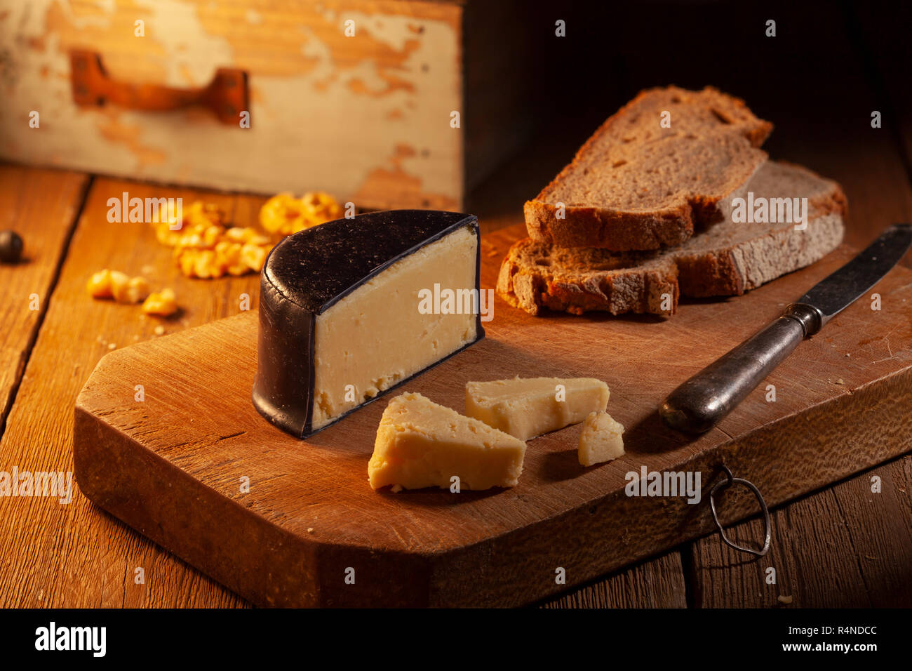 Coppia di formaggio cheddar coperto con cera nera su un tagliere di legno. Foto Stock