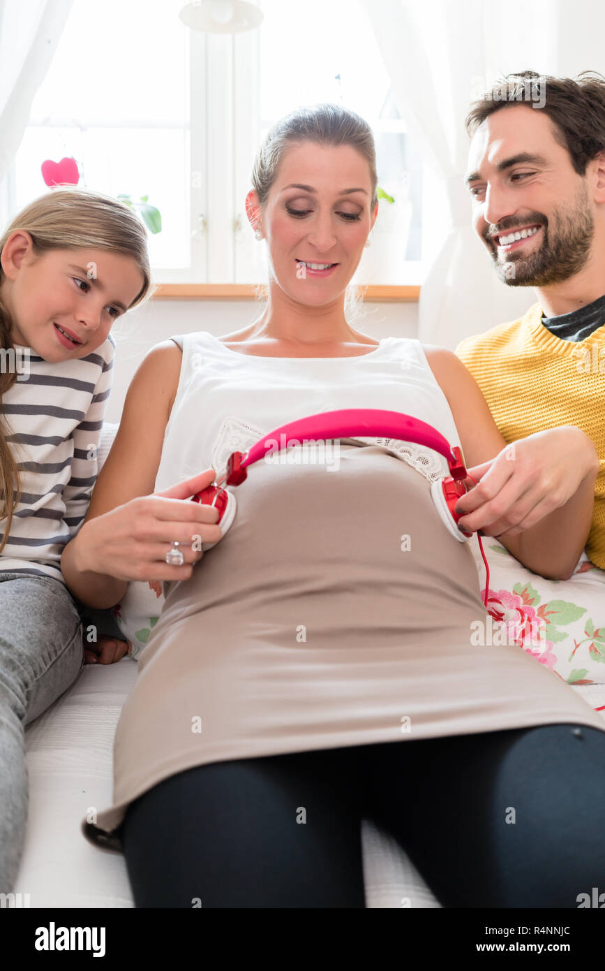 La famiglia e la mamma in gravidanza utilizzando cuffie sulla pancia del  bambino Foto stock - Alamy