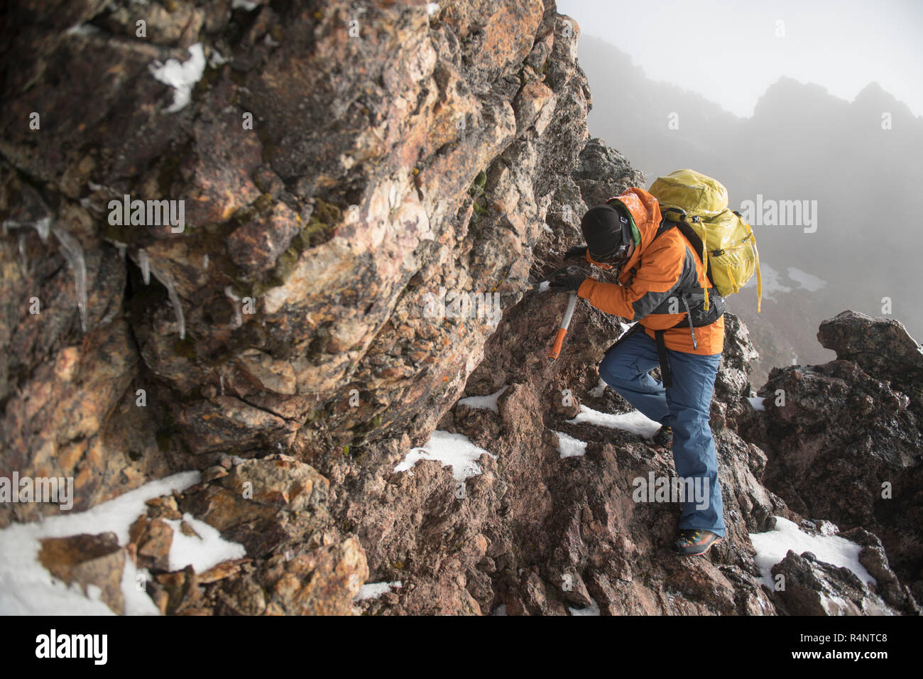 Un uomo si arrampica attraverso una sezione di roccia usando un piolet o ghiaccio ax, sulla sua ascesa al Iztaccihuatl volcanoe presso ilâ Izta-Popo Zoquiapan Parco Nazionale a Puebla, in Messico Foto Stock