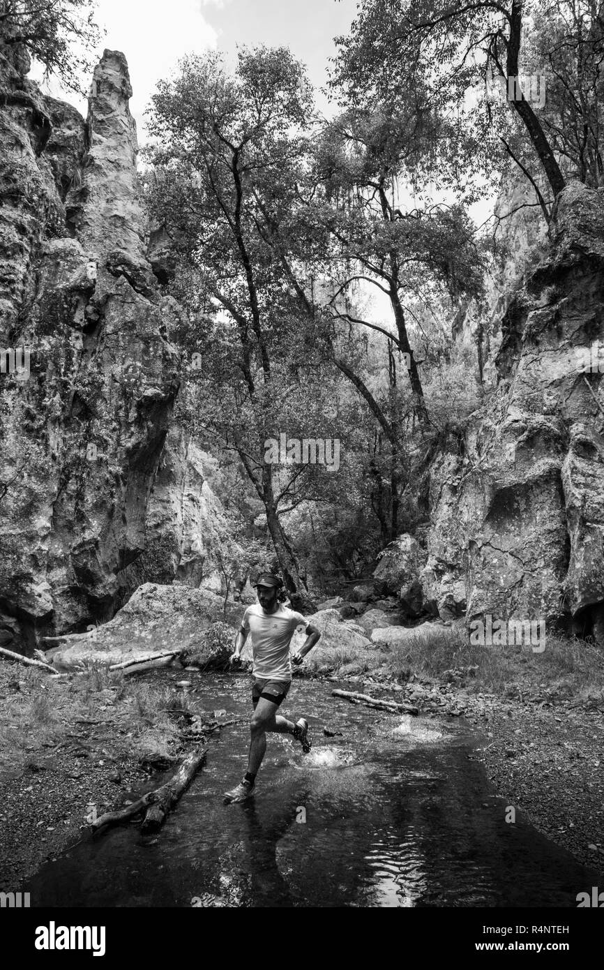 Un uomo che attraversa un ruscello mentre lungo un sentiero a El Arquito in Huasca de Ocampo, hidalgo, Messico. Foto Stock