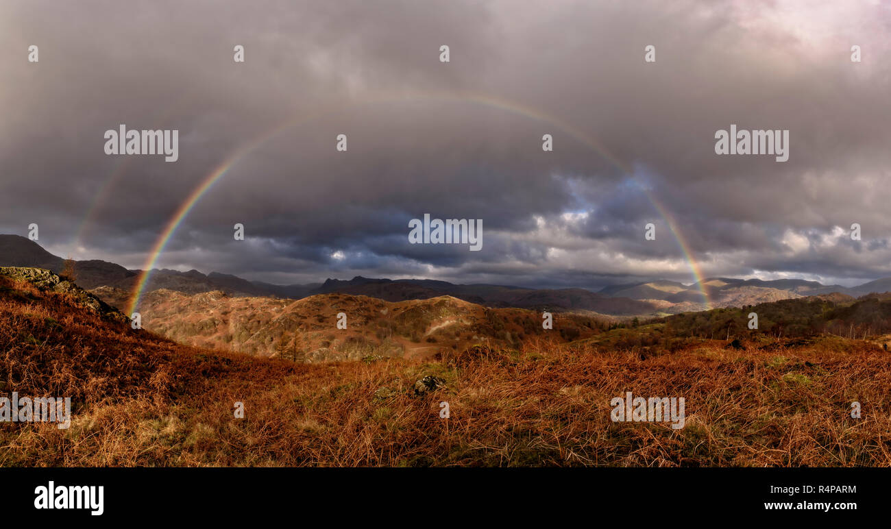 The Langdale Pikes incorniciato da un arcobaleno come si vede dalle pendici della rupe di nero Foto Stock