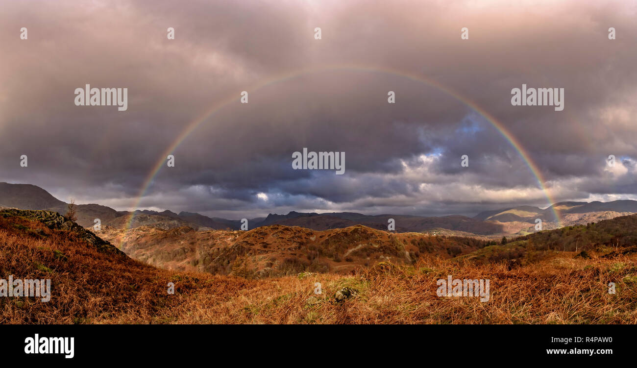 The Langdale Pikes incorniciato da un arcobaleno come si vede dalle pendici della rupe nera nei pressi di Tarn Hows Foto Stock