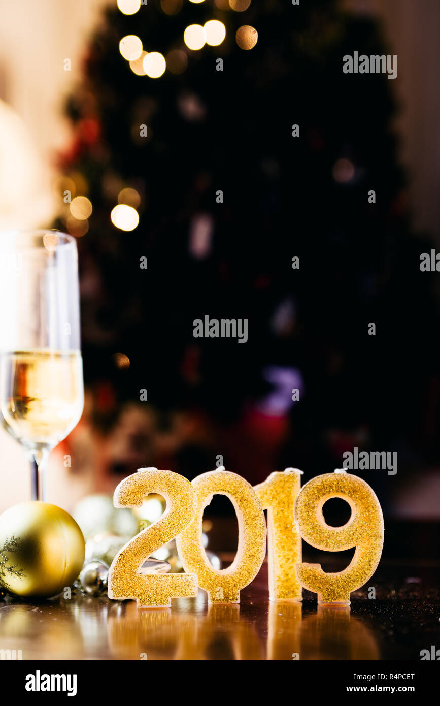 Il veglione di Capodanno celebrazione sfondo con coppia di flauto,candele formando il numero 2019, glitter e sfondo sfocato, con albero di natale luce f Foto Stock