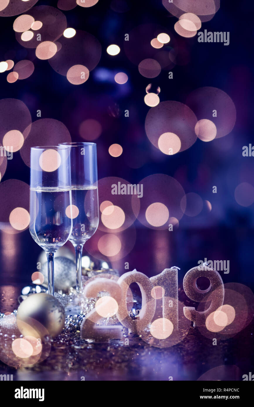 Il veglione di Capodanno celebrazione sfondo con coppia di flauto,candele formando il numero 2019, glitter e sfondo sfocato, con albero di natale luce f Foto Stock