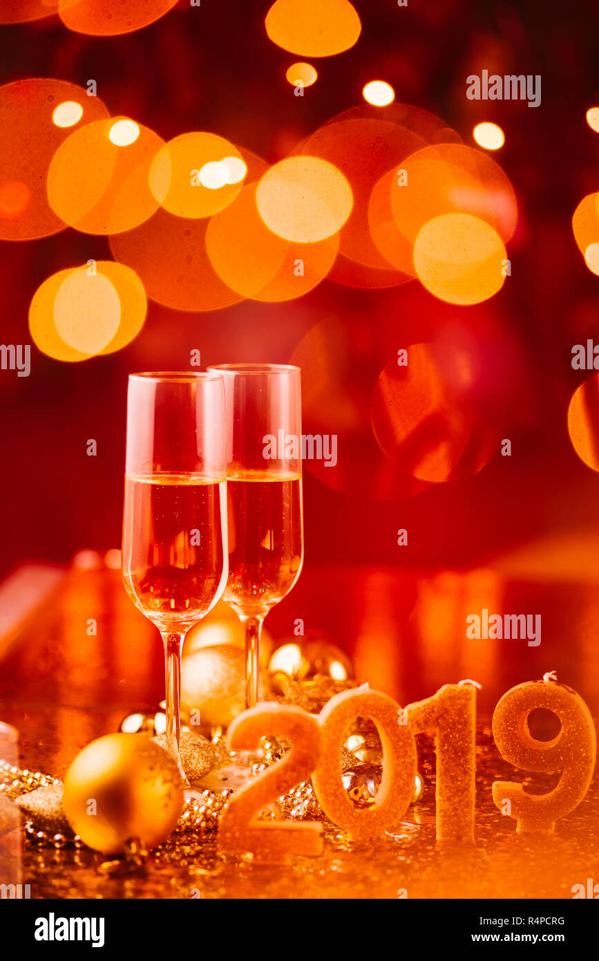 Il veglione di Capodanno celebrazione sfondo con coppia di flauto,candele formando il numero 2019, glitter e sfondo sfocato, con albero di natale luce f Foto Stock