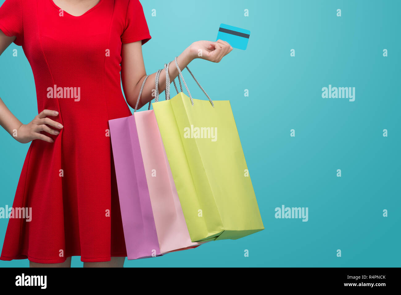 Ragazza asiatica che mostra la carta di credito in mano, su sfondo blu Foto Stock