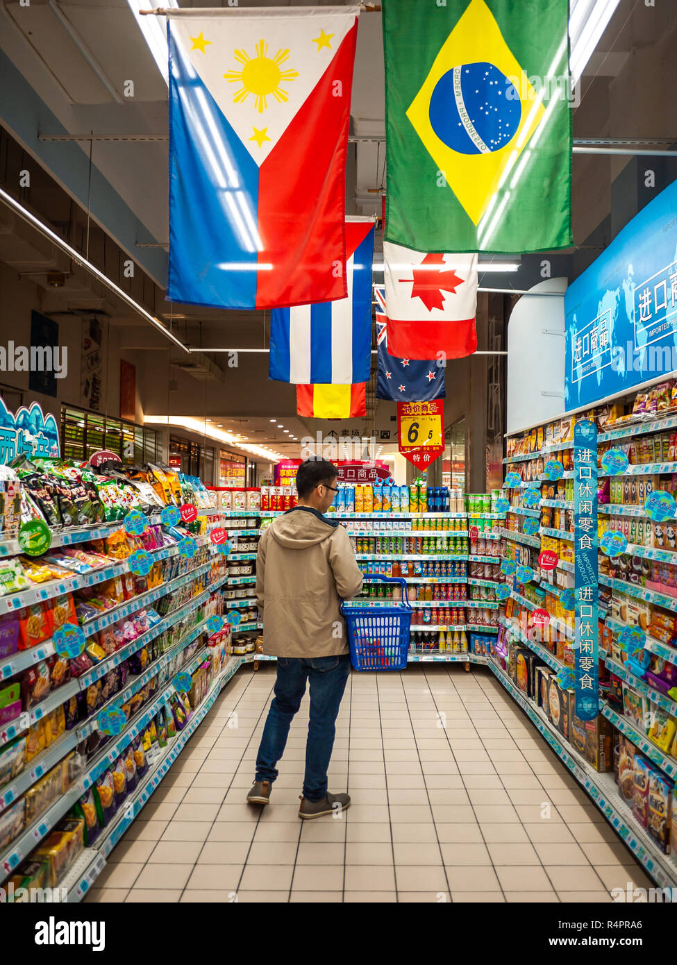 Un cliente maschio scelta di spuntini importati dall estero in un supermercato cinese. Foto Stock
