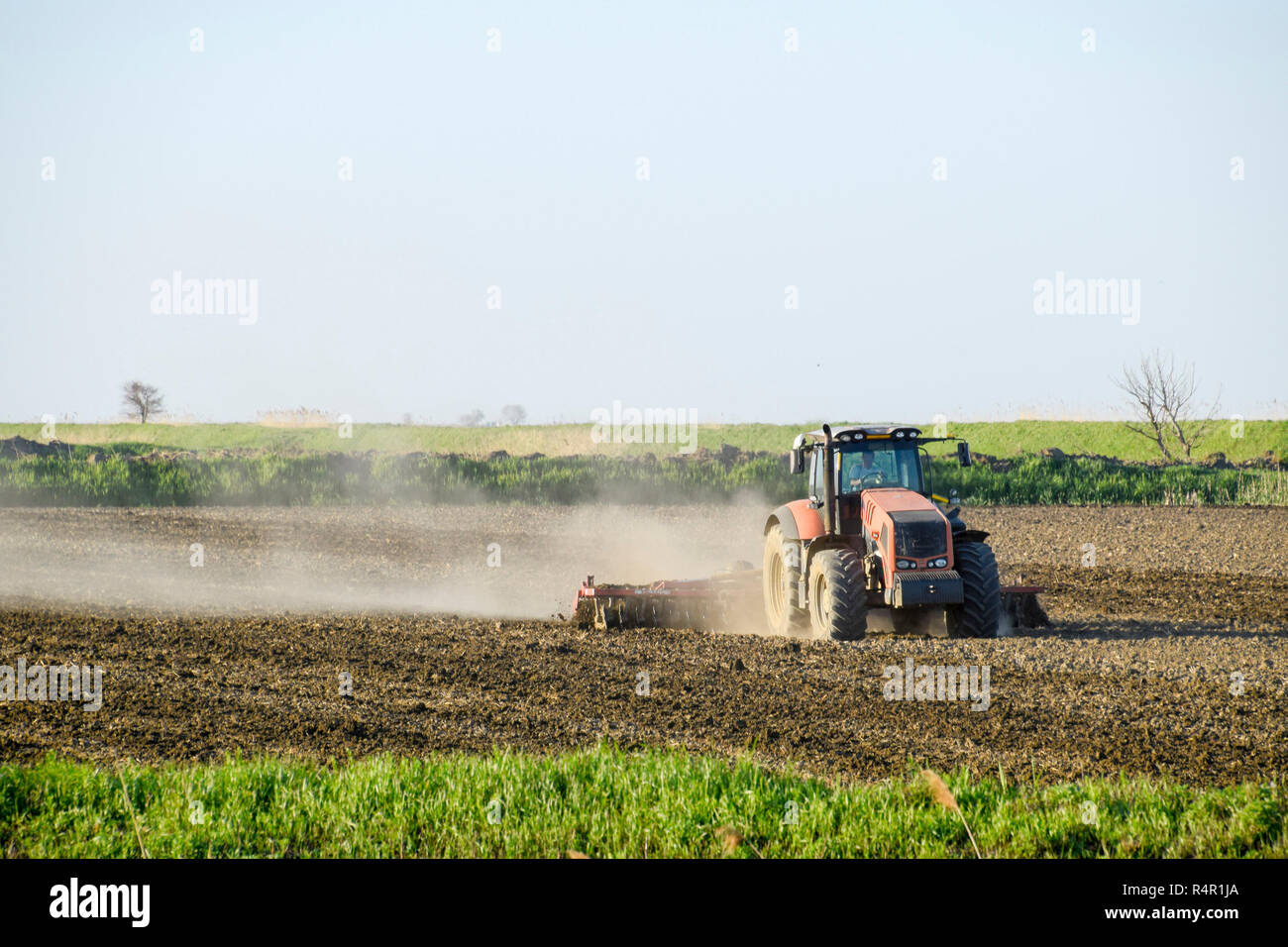 Un trattore con un aratro stabilisce il terreno. La coltivazione del suolo sul fie Foto Stock