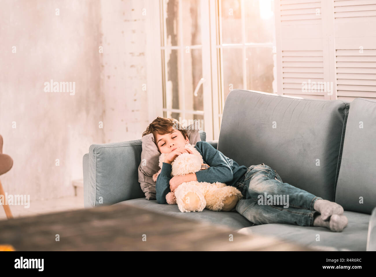 Bel Bambino addormentato nel suo salotto abbraccia il suo animali impagliati. Foto Stock