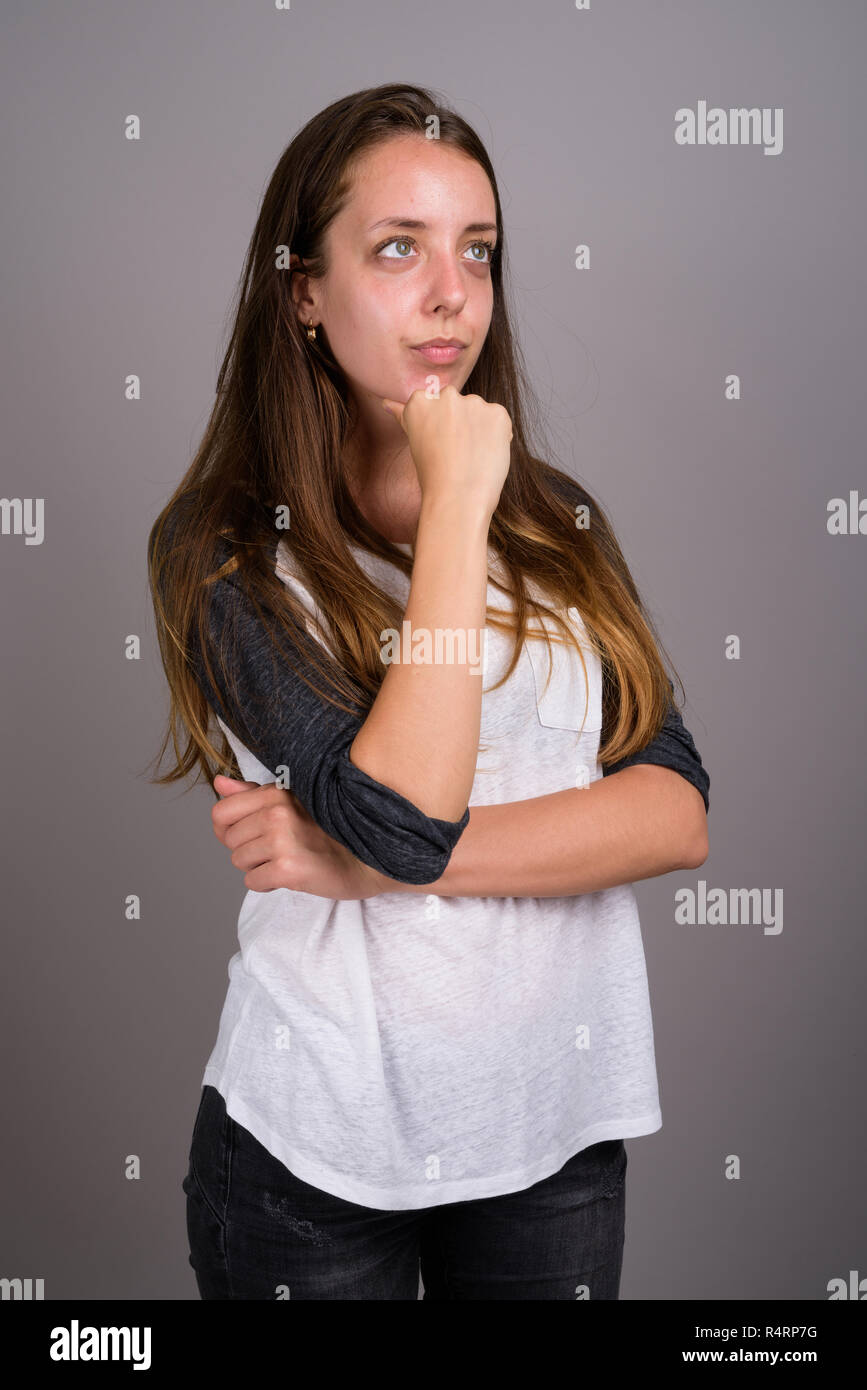 Ritratto di giovane donna bella contro uno sfondo grigio Foto Stock