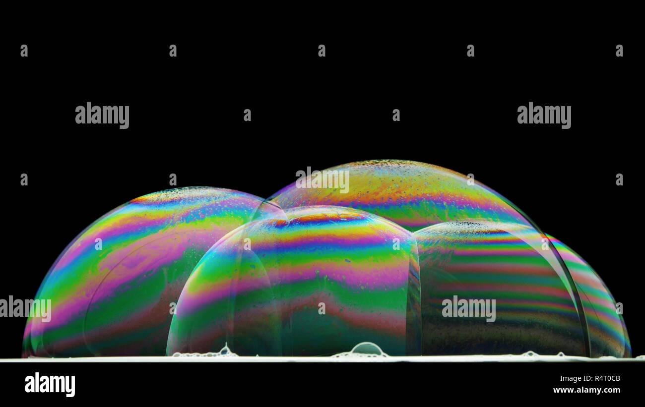 Iridescenze sulla superficie di alcune bolle di sapone illuminate dal basso Foto Stock