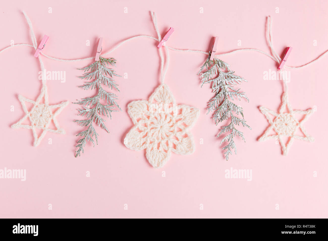 Composizione di natale di maglia fiocchi di neve bianca e stelle su sfondo rosa. Vista superiore, piana, laici copia spazio. Foto Stock