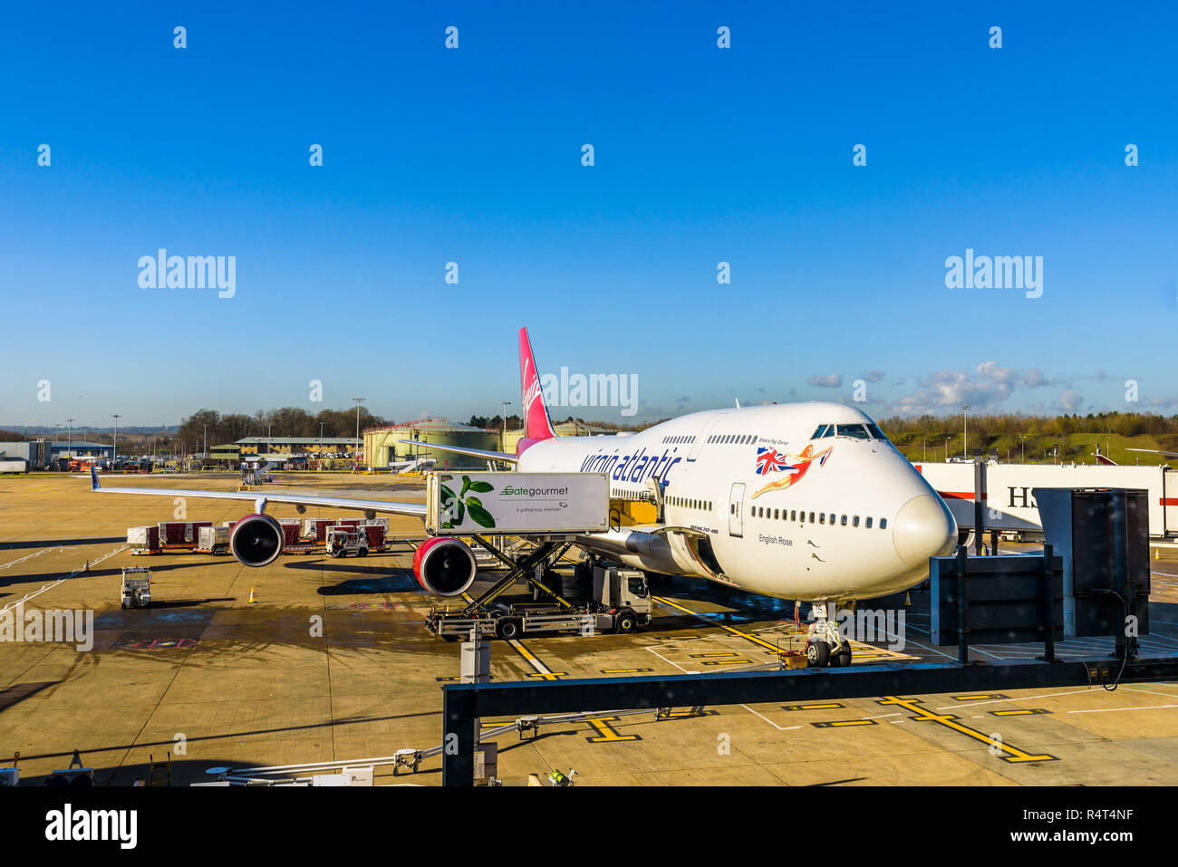 L' Aeroporto di Gatwick di Londra, Inghilterra. Boeing 747-443 Virgin Atlantic rosa inglese, volo a l'Avana, Cuba, l'imbarco di passeggeri su una soleggiata giornata invernale. Foto Stock
