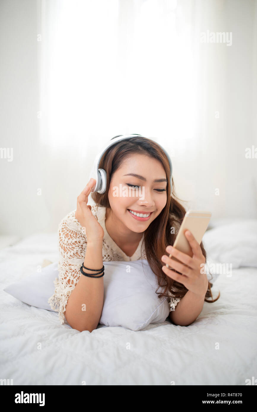 Donna relax nel letto e ascolto di musica rilassante nel suo soggiorno Foto Stock