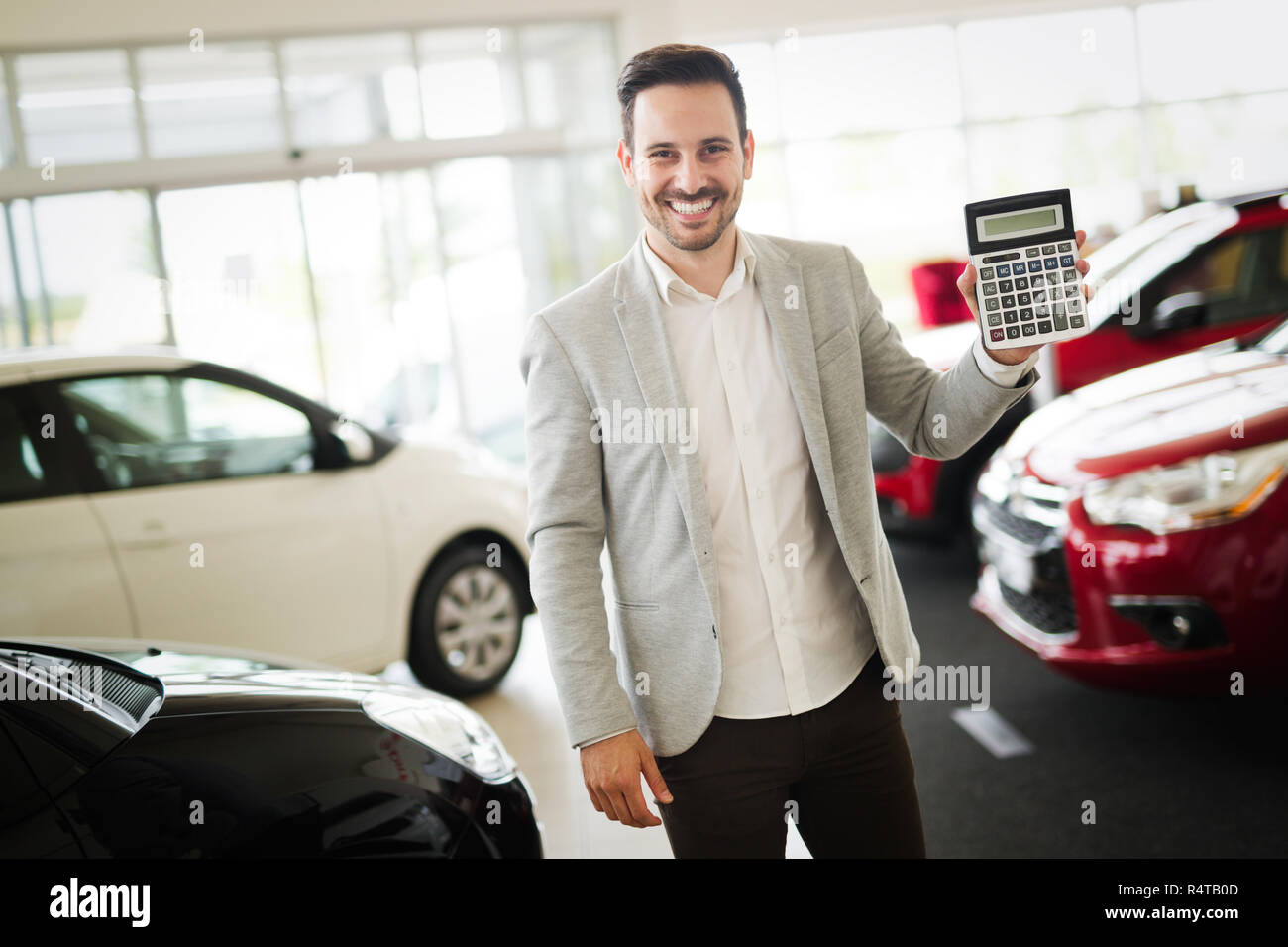 Giovani attraenti venditore è in possesso di una calcolatrice e puntando al incredibilmente buon prezzo per un auto Foto Stock